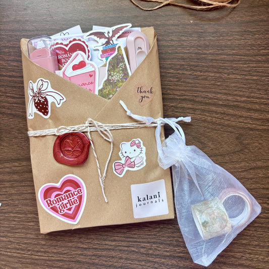 Kraft paper-wrapped journal with stickers, twine, and a small bag on a wooden surface