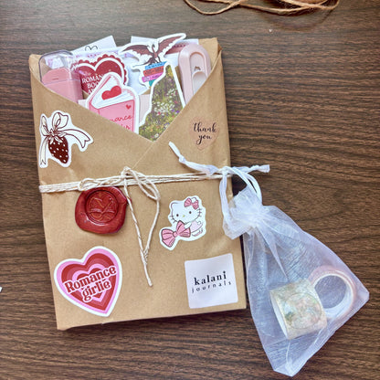Kraft paper-wrapped journal with stickers, twine, and a small bag on a wooden surface