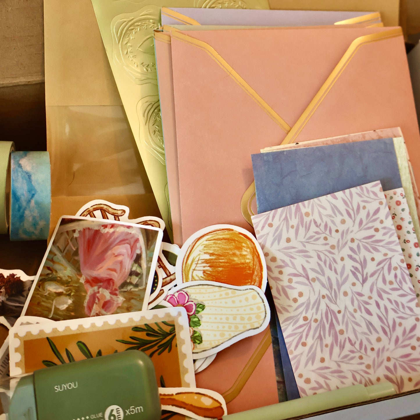 Collection of stationery items including envelopes, cards, and decorative elements on a textured surface.
