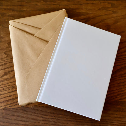 Kraft-wrapped journal and white notebook on a wooden surface.