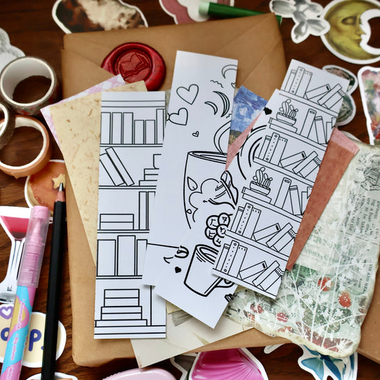 Coloring book pages and stickers with illustrations on a wooden surface with stationery items.